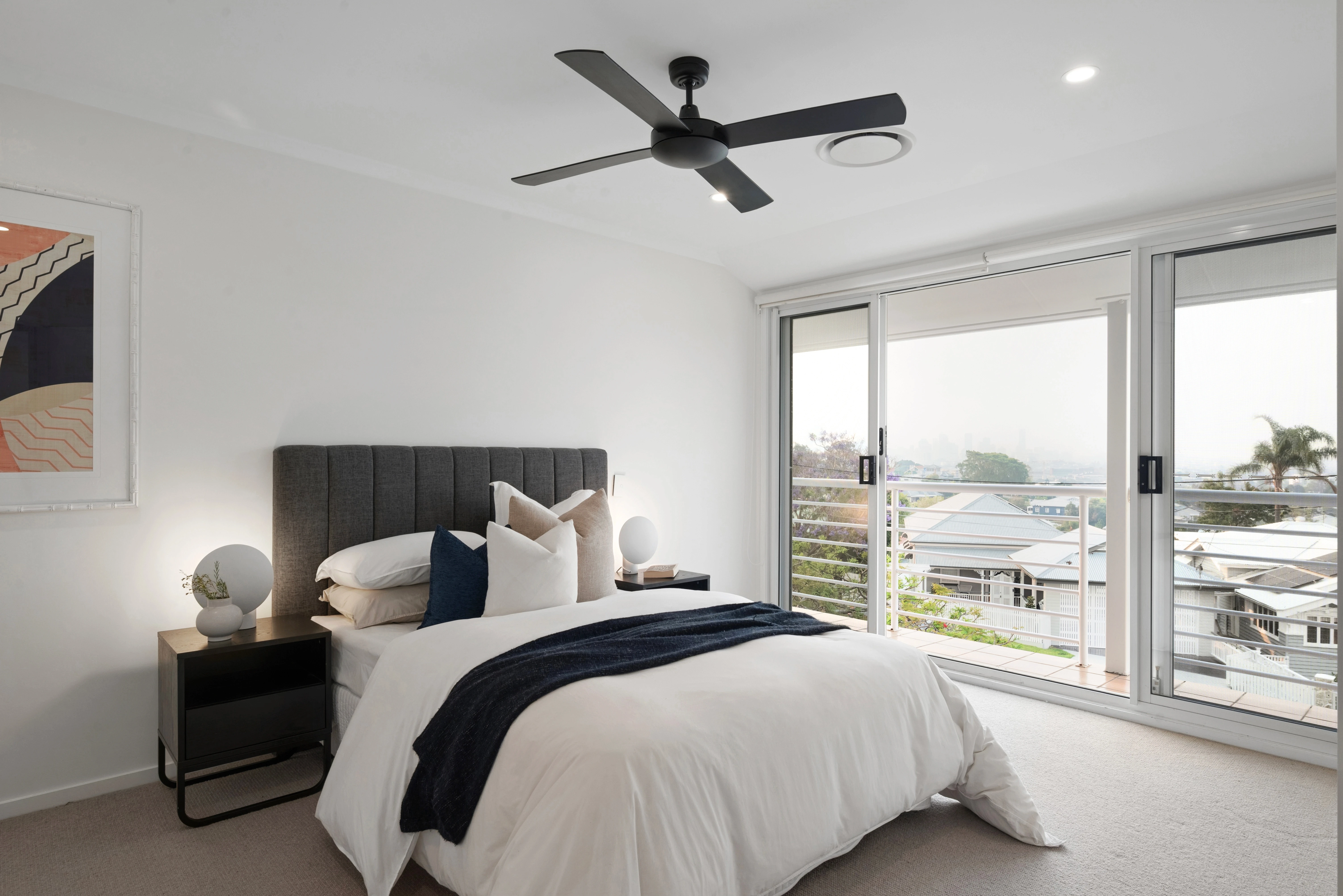 Edited real estate photo of a bedroom with ceiling fan and balcony doors