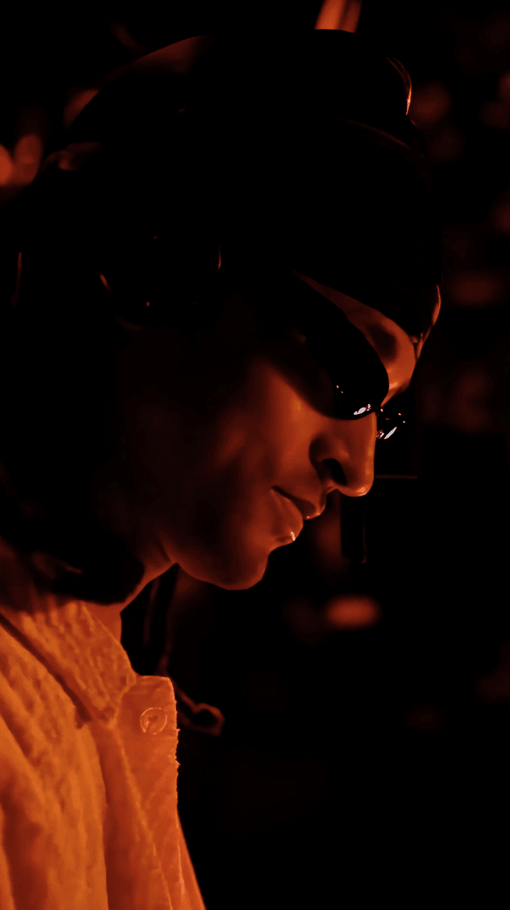 Dancer in black outfit with arms raised, arching backwards