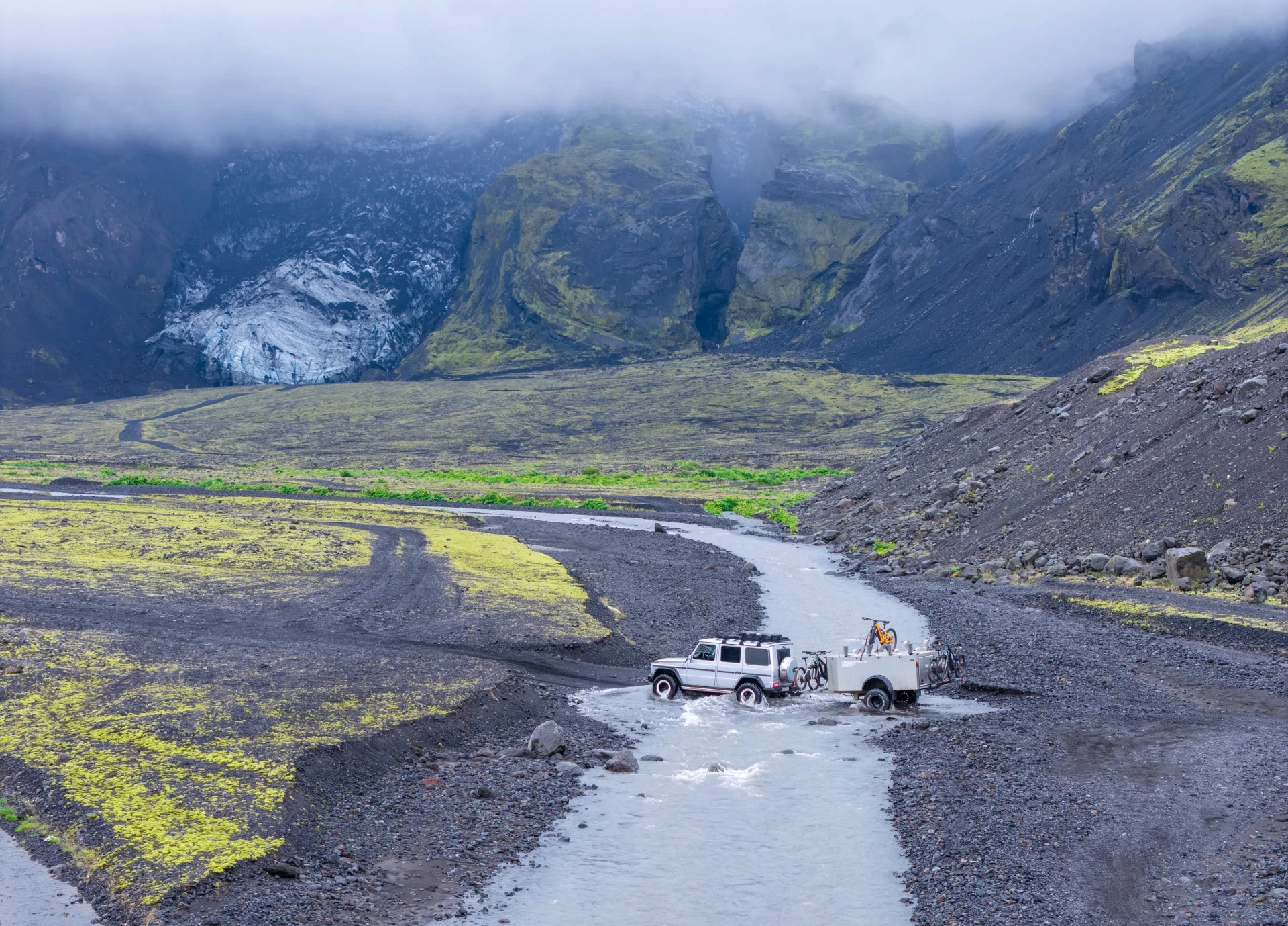 a modified vehicle crosses river with biketrailers