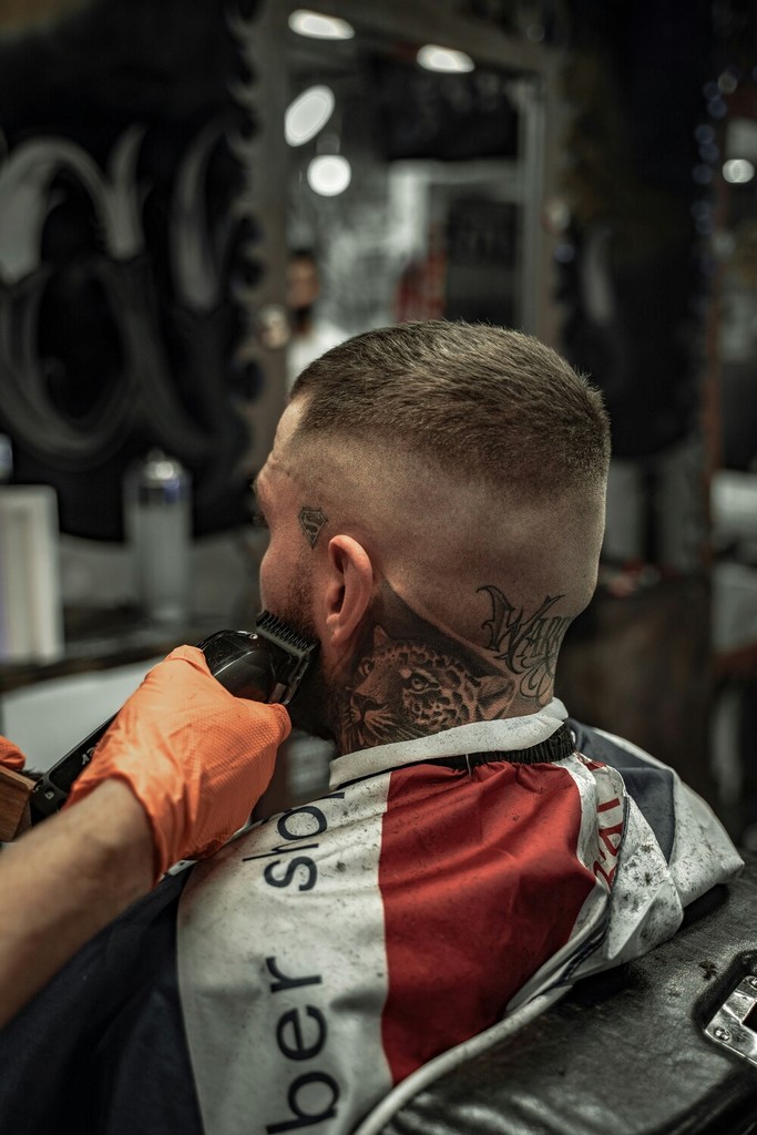 Senior Client Receiving a Traditional Shave: An elderly man getting a classic wet shave with a straight razor from an experienced barber in a nostalgic barbershop with vintage decor.