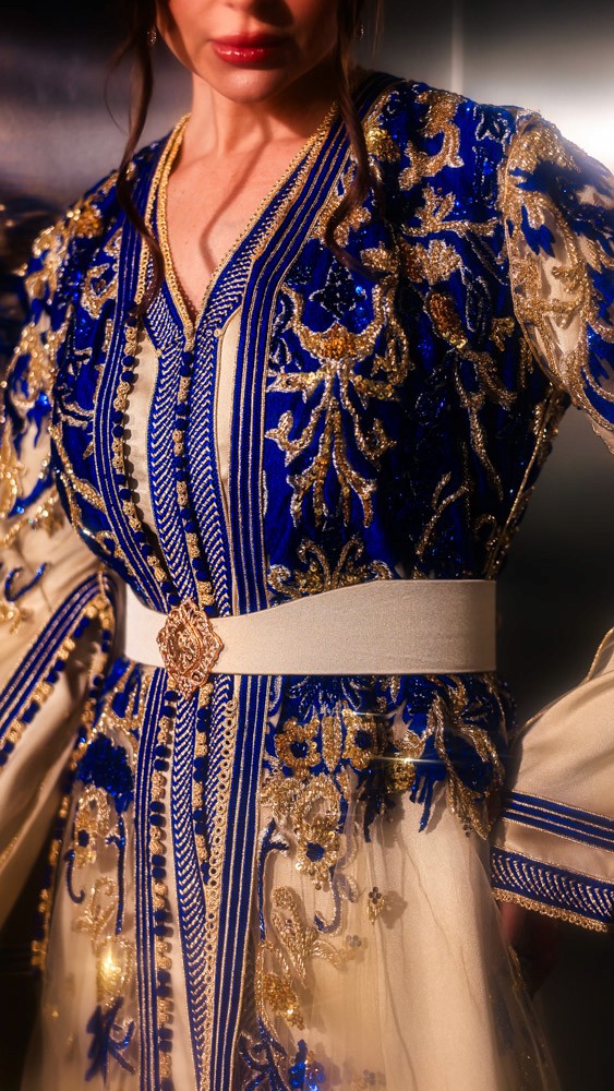 Ivory Moroccan caftan with deep blue embroidery, handcrafted couture piece combining Bahrain atelier and Moroccan artisans