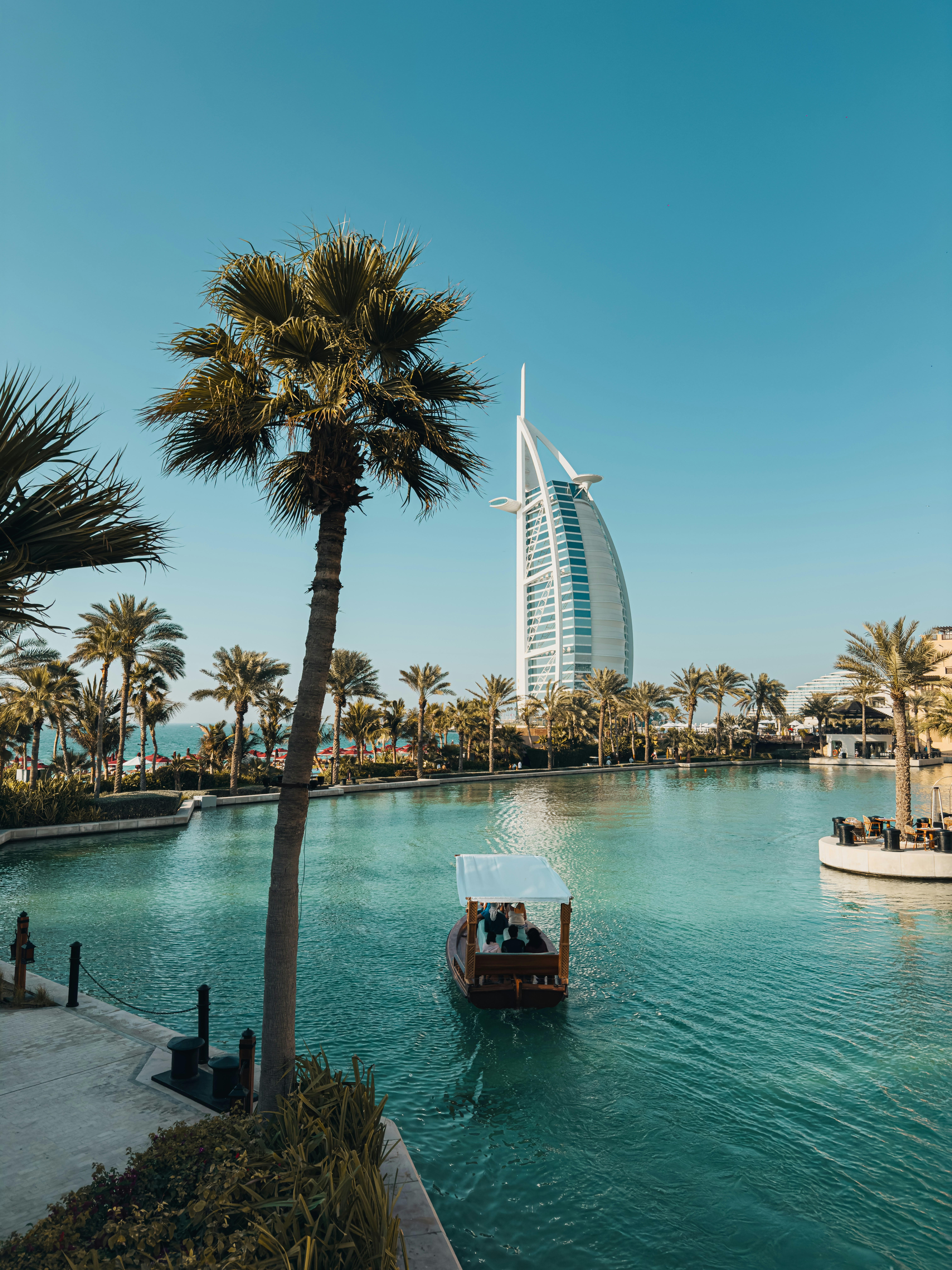 Boat on water with palm trees and modern building.