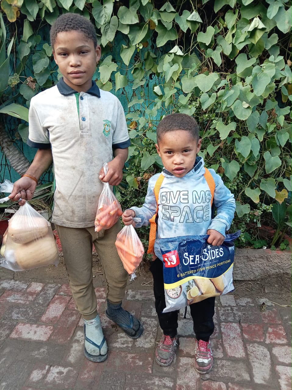 Three children walk along a dirt path.