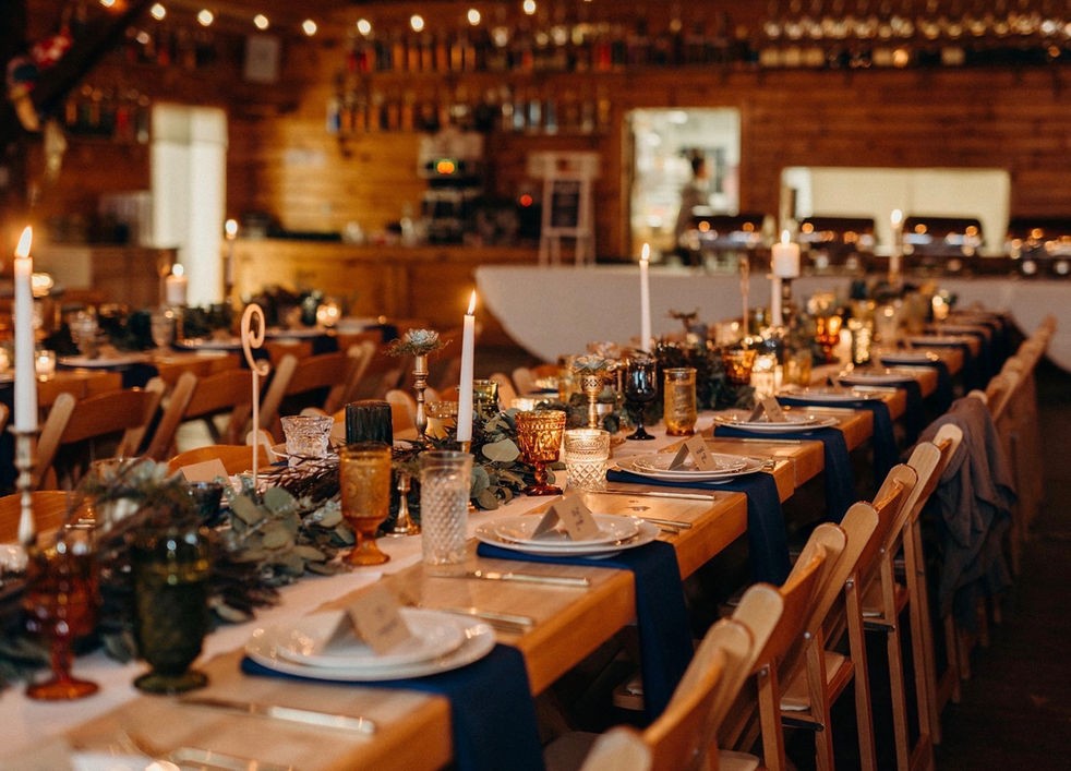 Candlelit wedding tables with greenery in the wood-paneled dining hall at Camp Lenox