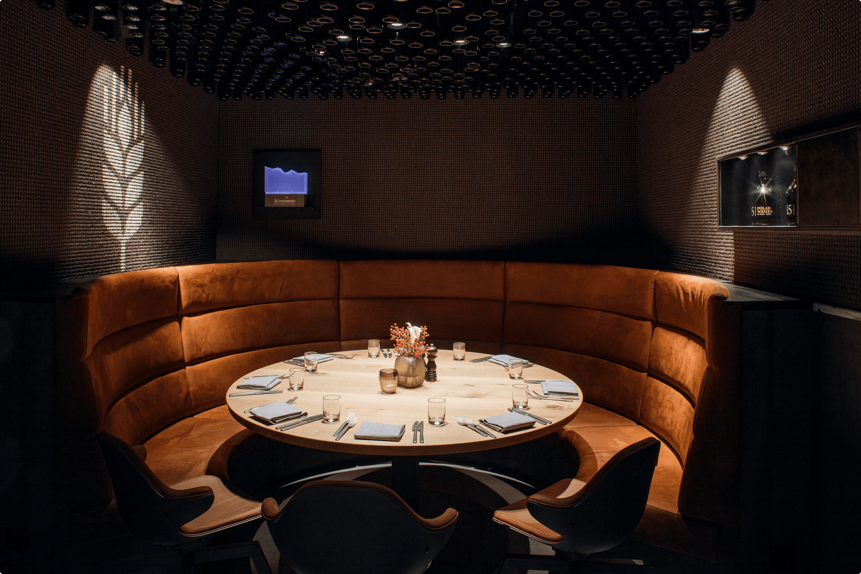 Round table in plush booth seating with place settings.