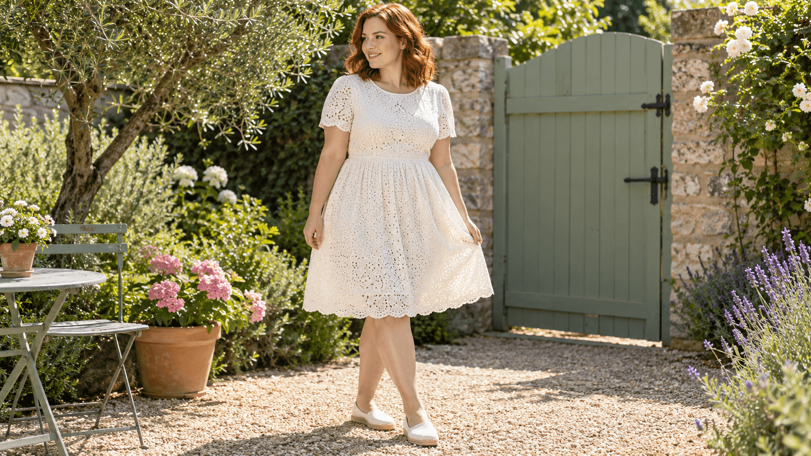 Une femme porte une robe ivoire en broderie anglaise à manches courtes, avec des espadrilles, dans un jardin.