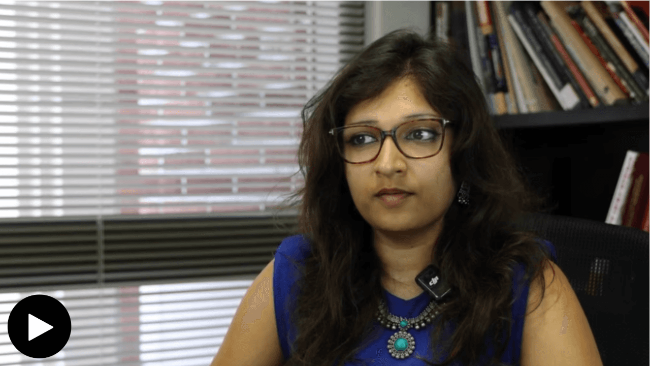 Syona Pulliady at her desk with books and a window behind her
