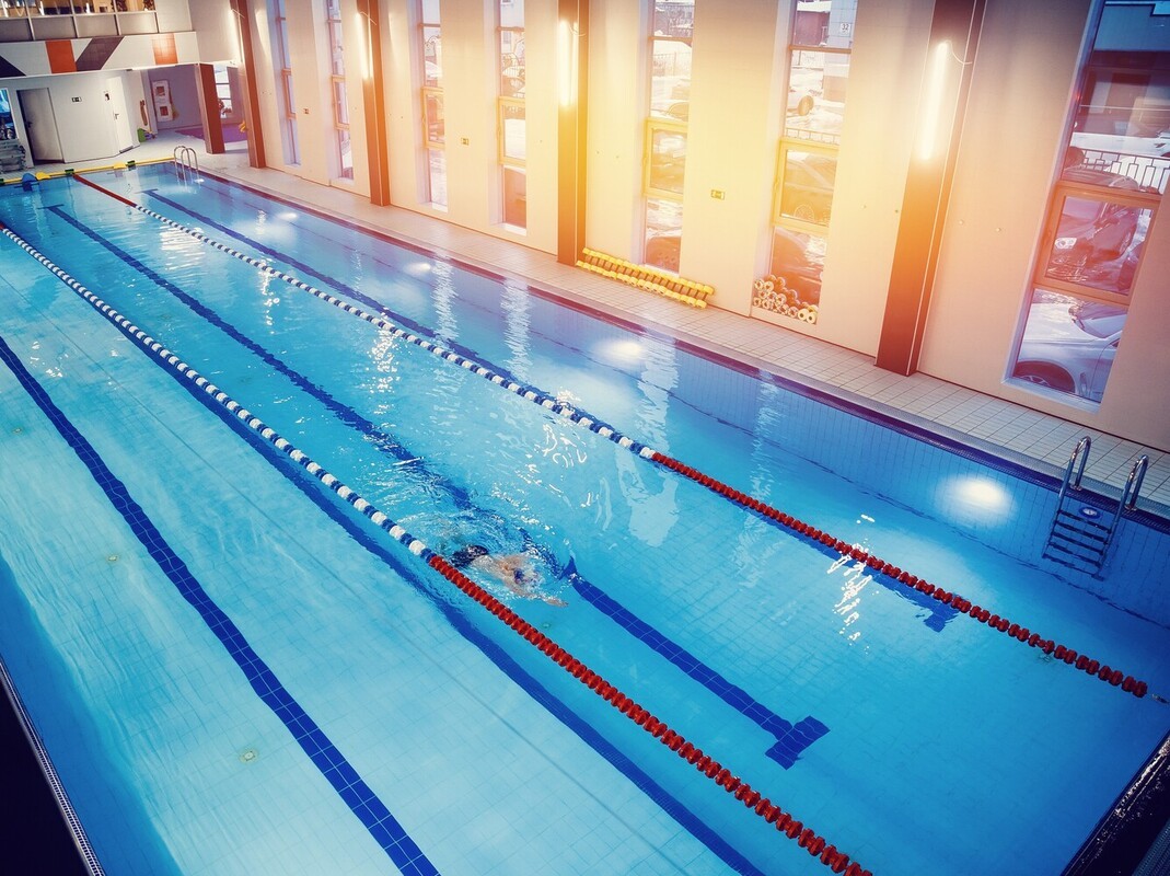 man swimming to lose weight by using the large pool in his gym