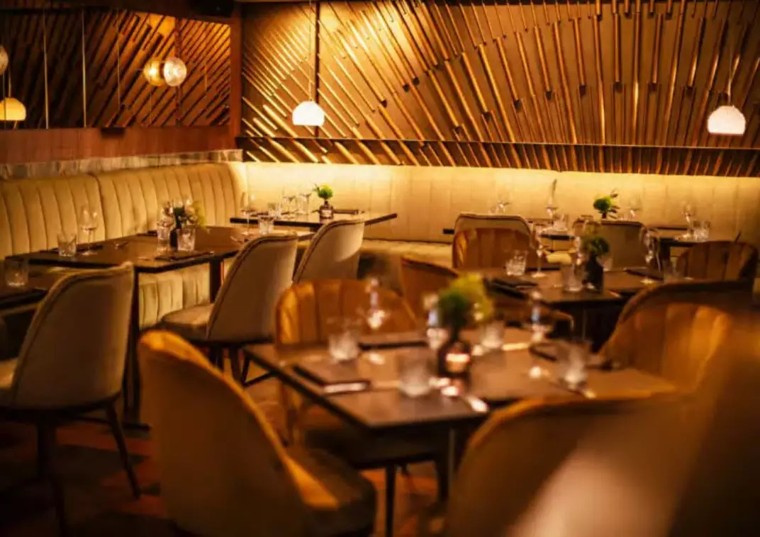 Gemütliches Restaurantinterieur von St. Ribs mit Holzwänden, gedeckten Tischen und warmem Licht