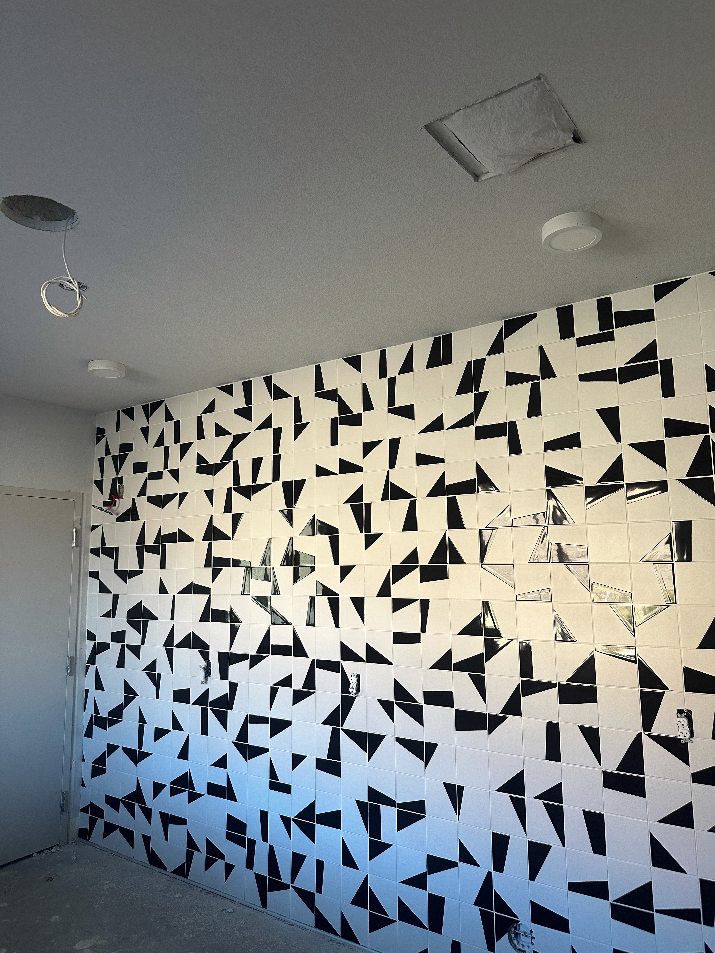 Modern kitchen with a bold black and white geometric tile backsplash and recessed ceiling lights.
