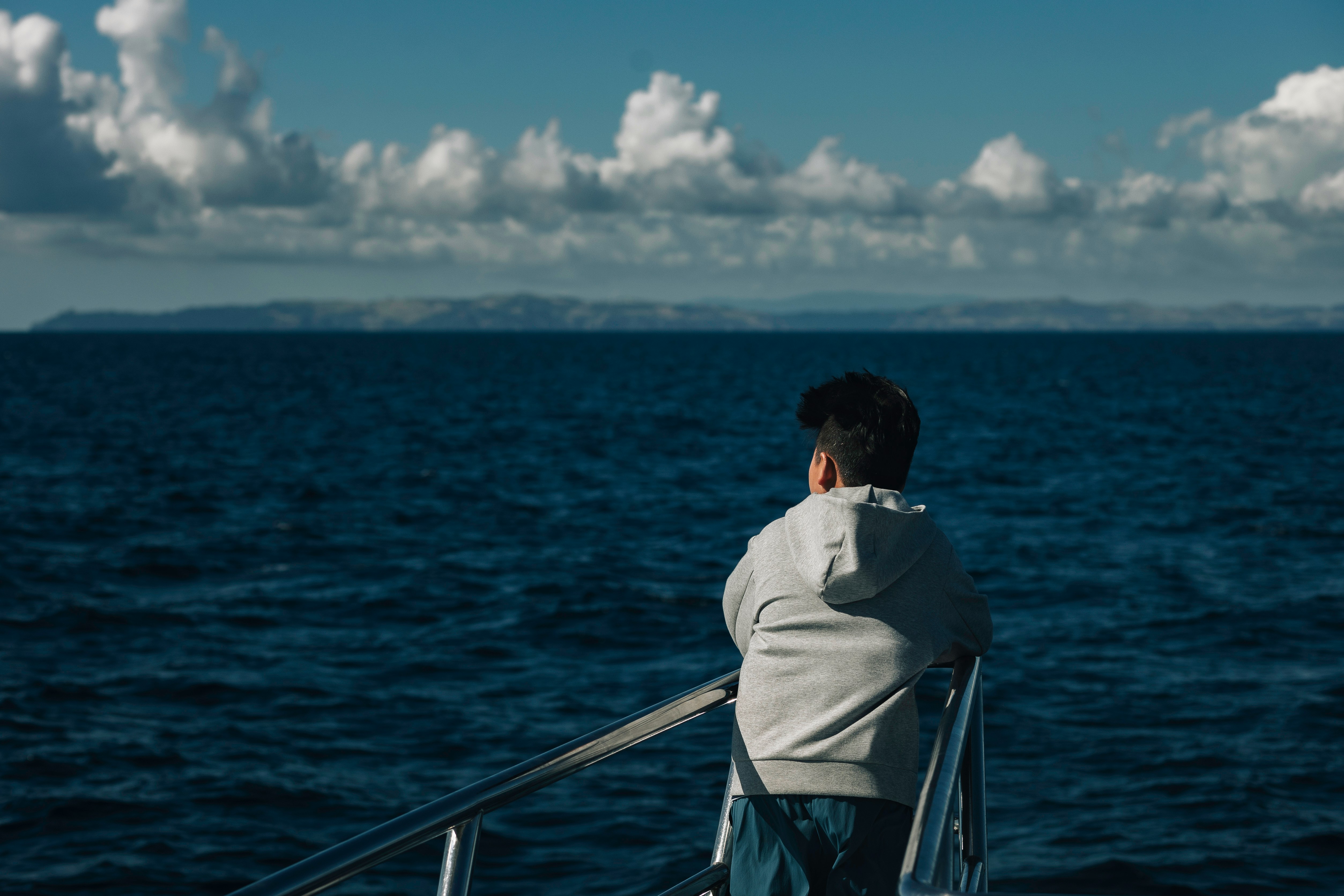 A man standing on a boat looking out at the ocean