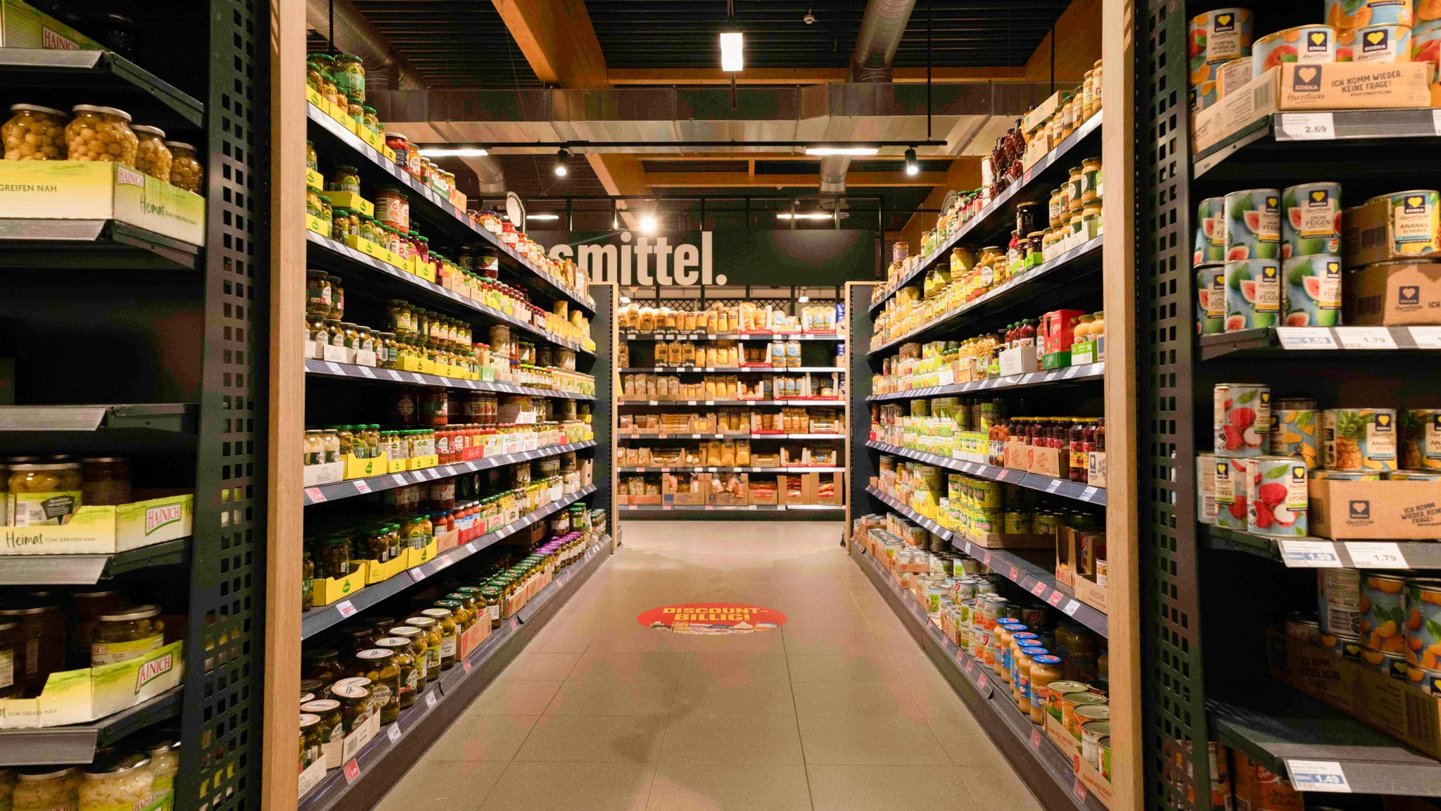 Blick in einen gut gefüllten Supermarktgang mit Lebensmitteln. Die FMCG-Branche steht für hohe Verfügbarkeit, schnelle Warenrotation und effiziente Regalpflege am Point of Sale.