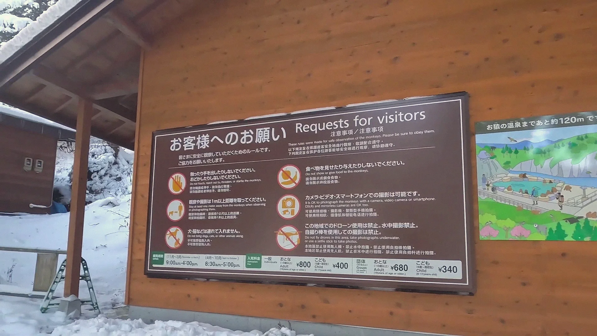 The bilingual 'Requests for Visitors' (お客様へのお願い) rules board at Jigokudani Monkey Park, beside a trail map noting ~120 m to the monkeys' hot spring.