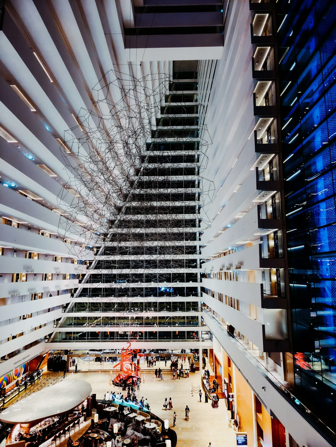 Looking up the Marina Bay Sands hotel atrium: stacked white balconies rising to a sloping blue glass wall