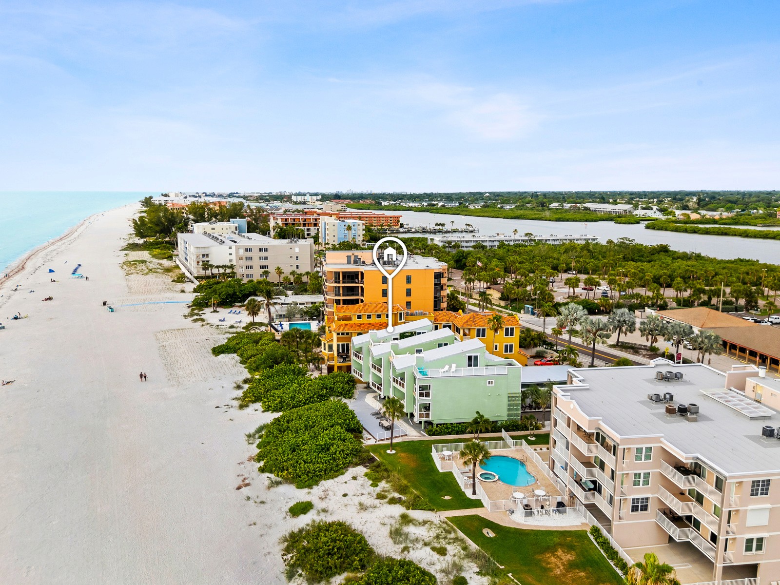 Aerial view of a beachfront Gulf Coast vacation rental with white sand, pool area and neighboring condos, shot by Gator Gaze Media on a nearby Pinellas barrier island