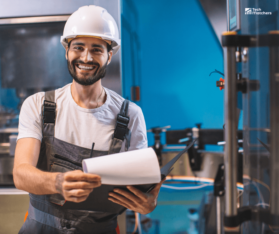Lachende storingsmonteur met veiligheidshelm en clipboard in een industriële omgeving. De technicus controleert machines en voert onderhoud uit in een moderne productielijn – symbool voor vakmanschap, betrouwbaarheid en technische expertise binnen de Nederlandse industrie.