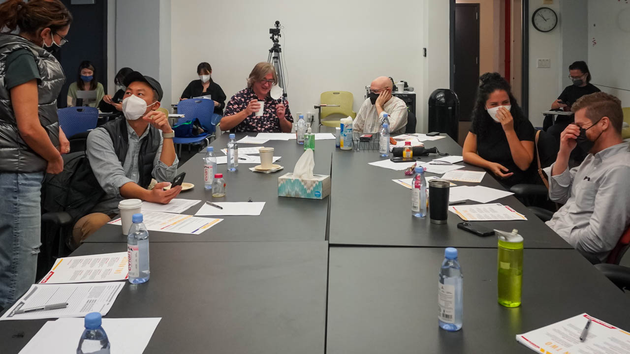 Many people sitting around a table with papers on it