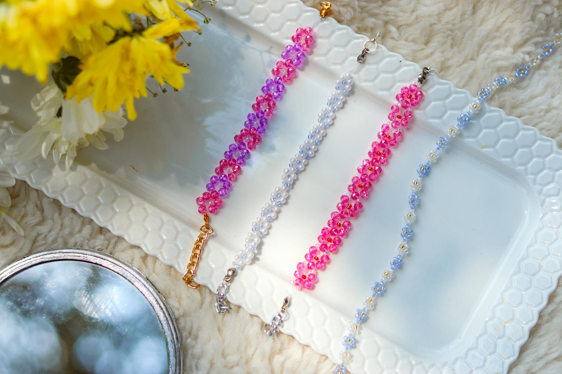 A vivid array of bead bracelets on a white tray with flowers. Perfect for fashion and lifestyle themes.