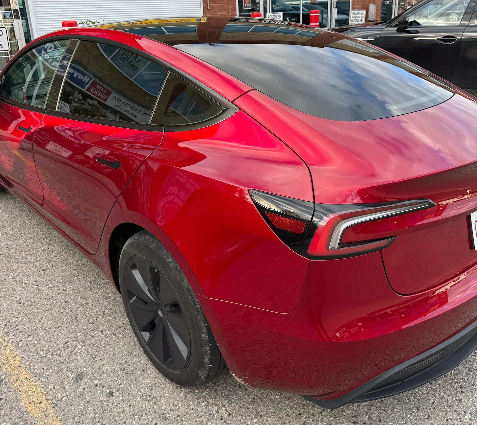 Red Tesla 3 with black rims parked outside.