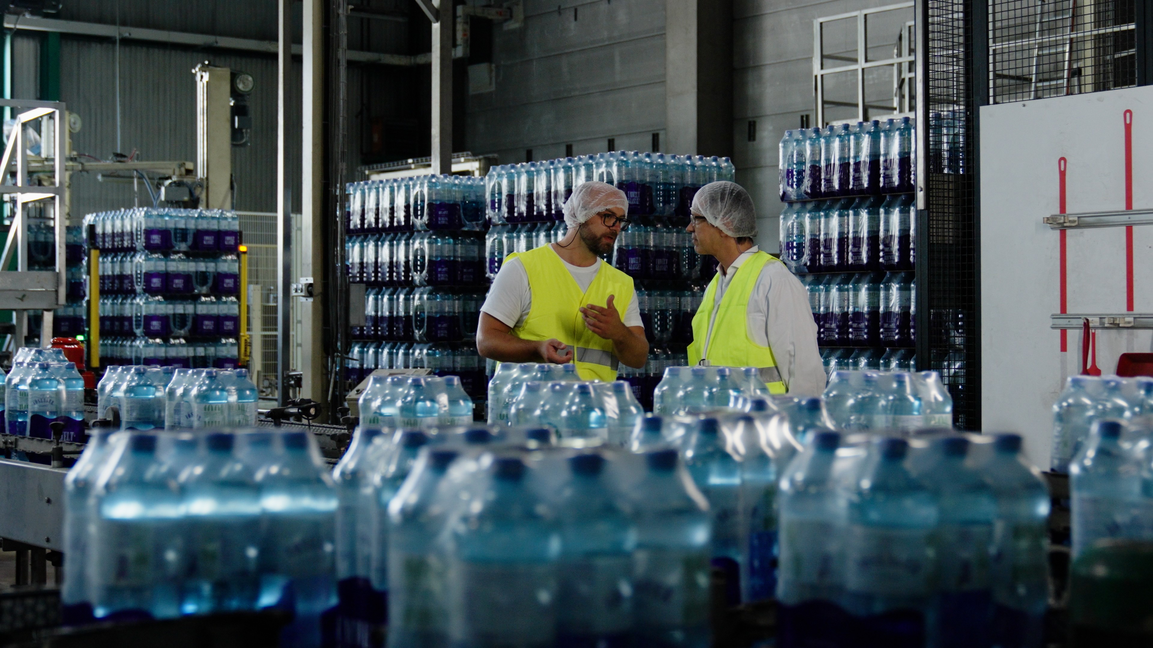 GASSNER FlexiLiner Referenzvideo: Zwei Männer mit Warnwesten zwischen verpackten Wasserflaschen im Lager