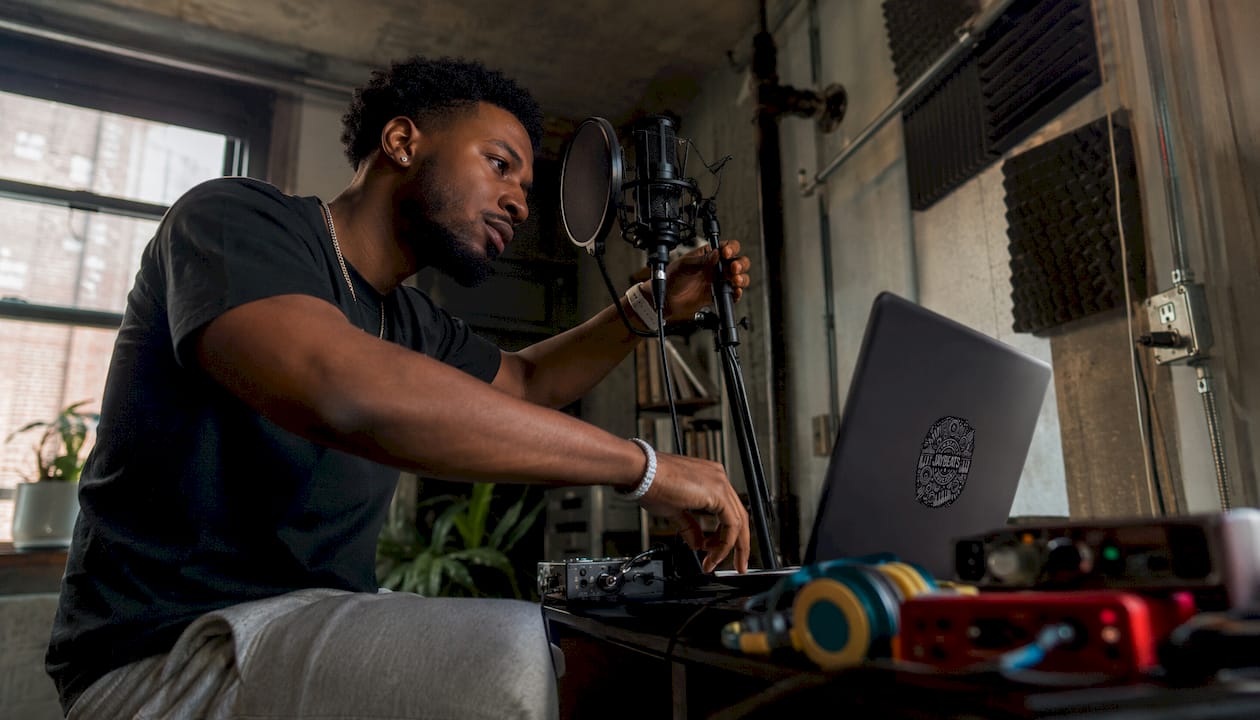 Rapper adjusting mic in treated home studio