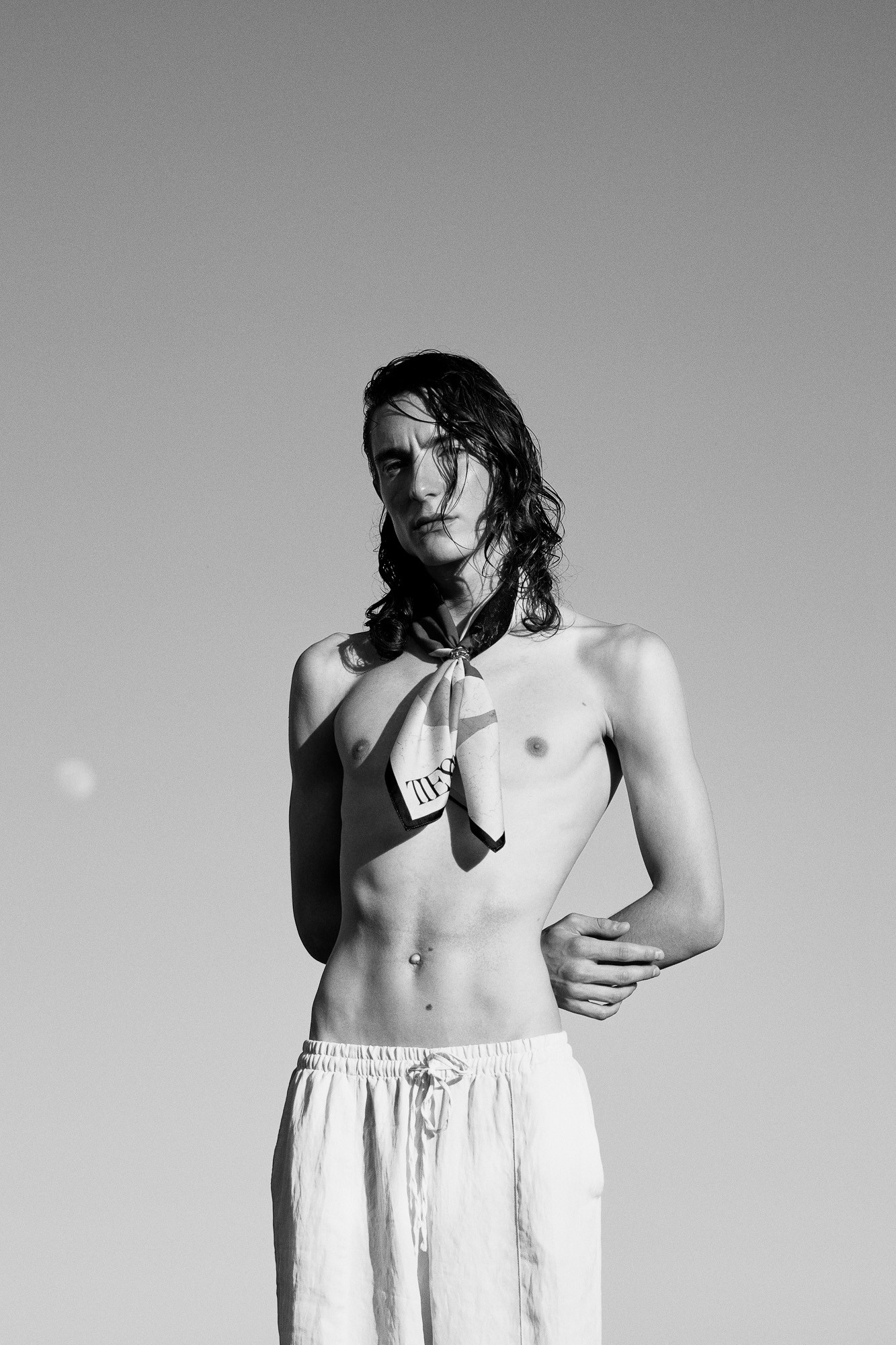 Black and white portrait of a long-haired male model wearing a neck scarf for Tieso Estudio