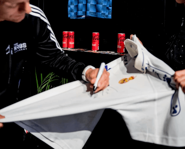 Sportveranstaltung in einer beleuchteten Indoor-Arena mit Basketballspiel und Publikum.