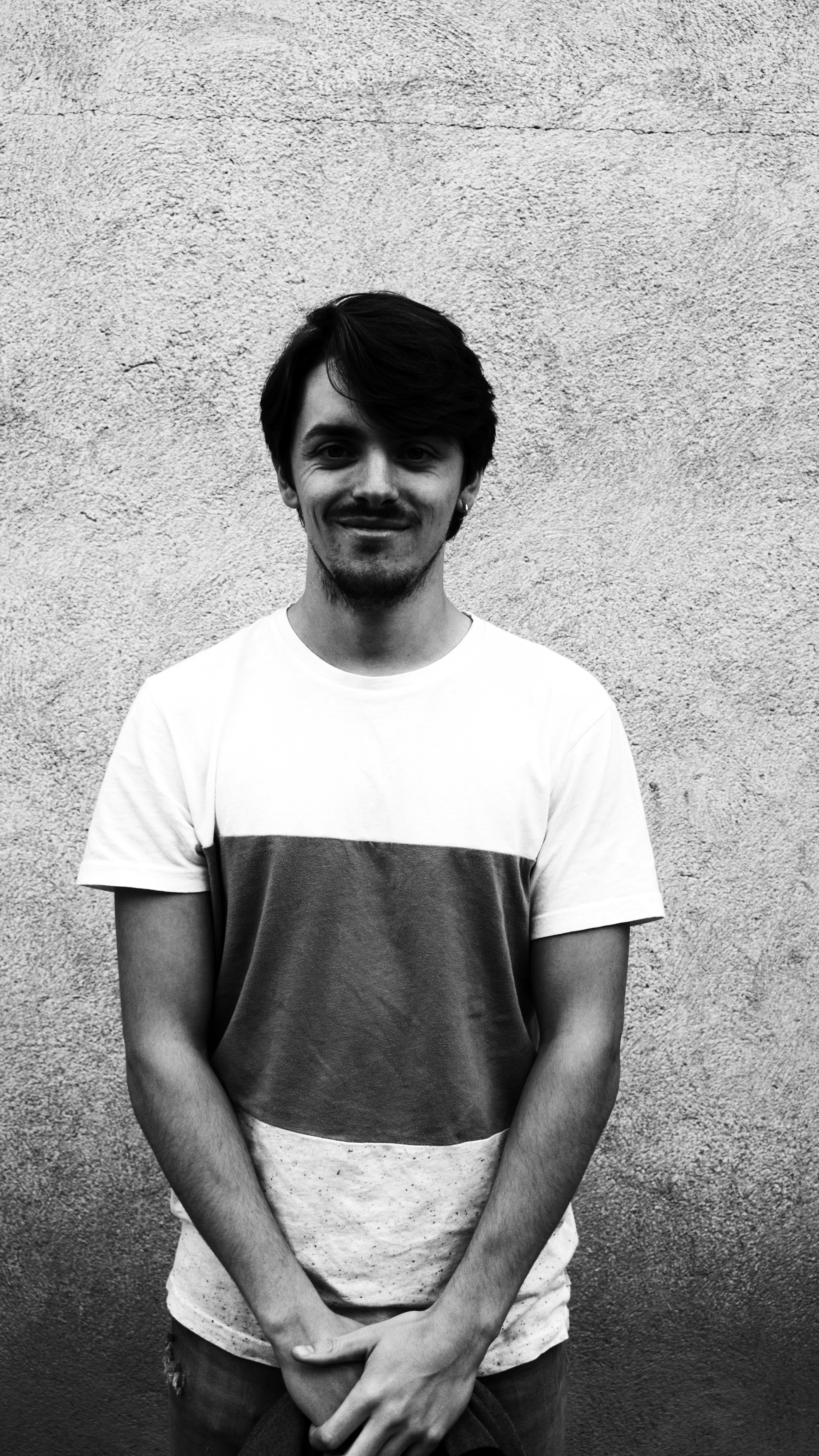A thoughtful young person with dark hair gazes to the side, captured in soft black and white lighting.
