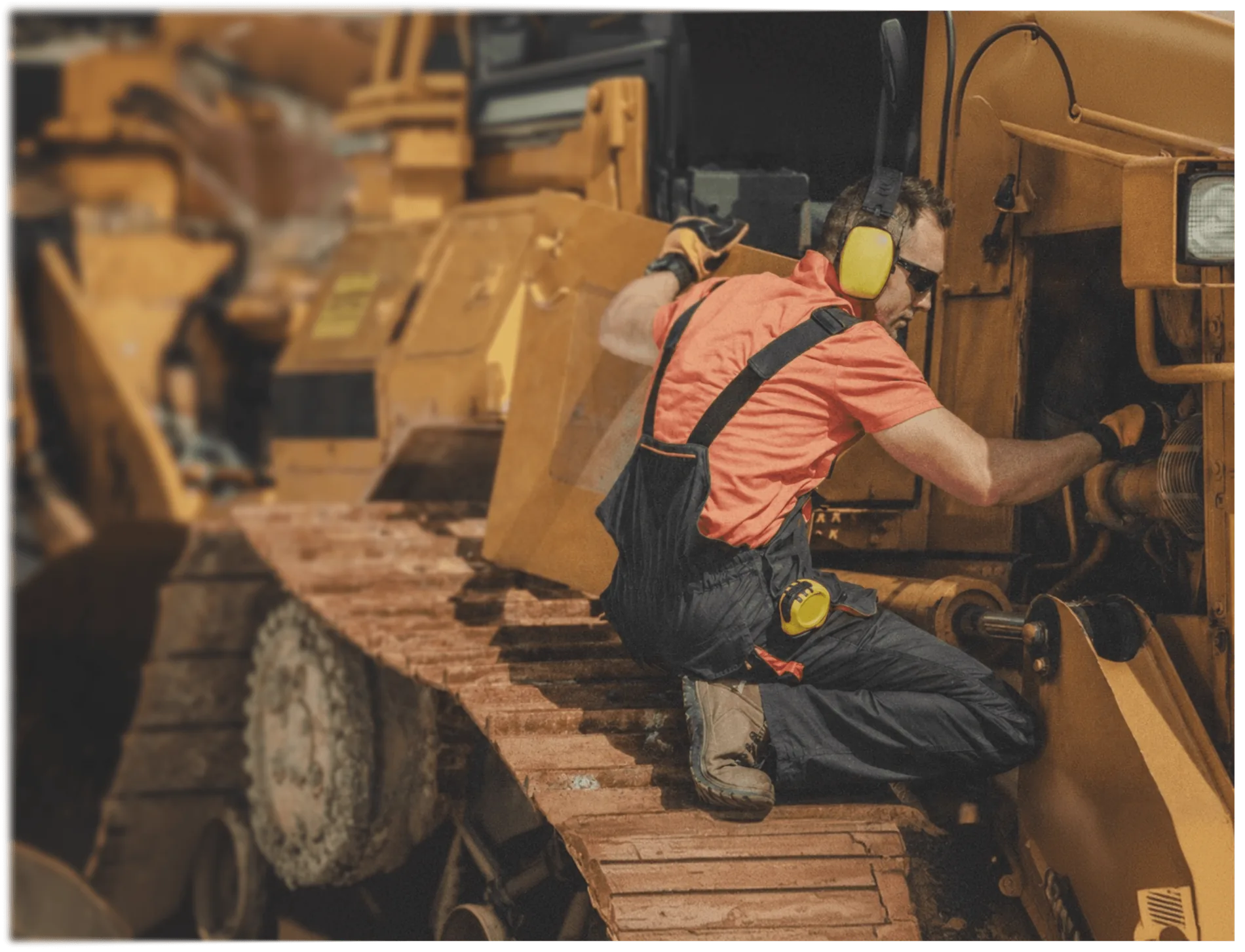 Mechanic in ear defenders working on the tracks of a heavy machine