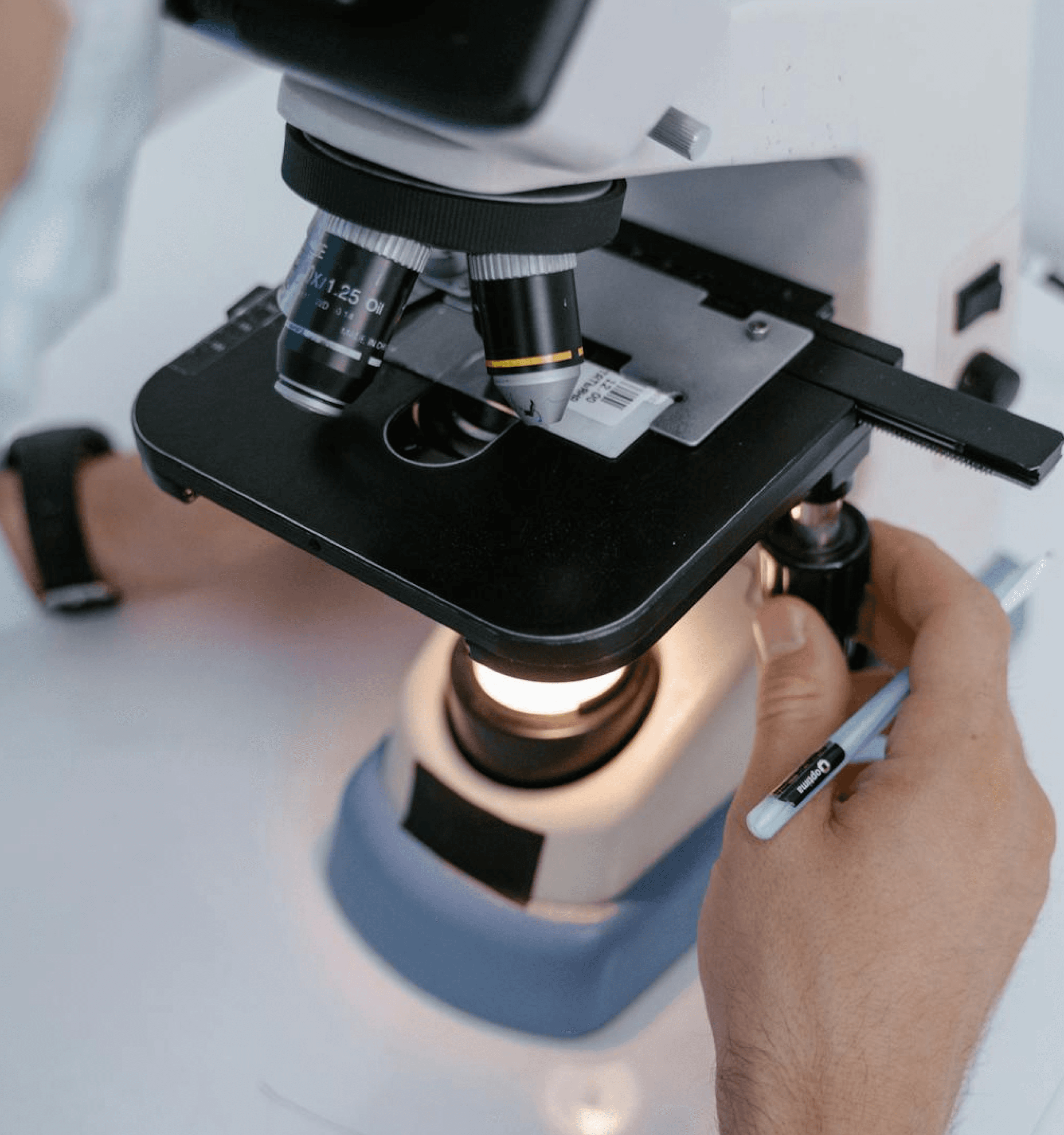 Scientist adjusting laboratory microscope stage to examine sample slide.