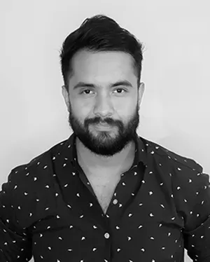 Minimal studio portrait of a confident woman in a white shirt, arms crossed, on a soft gray background.