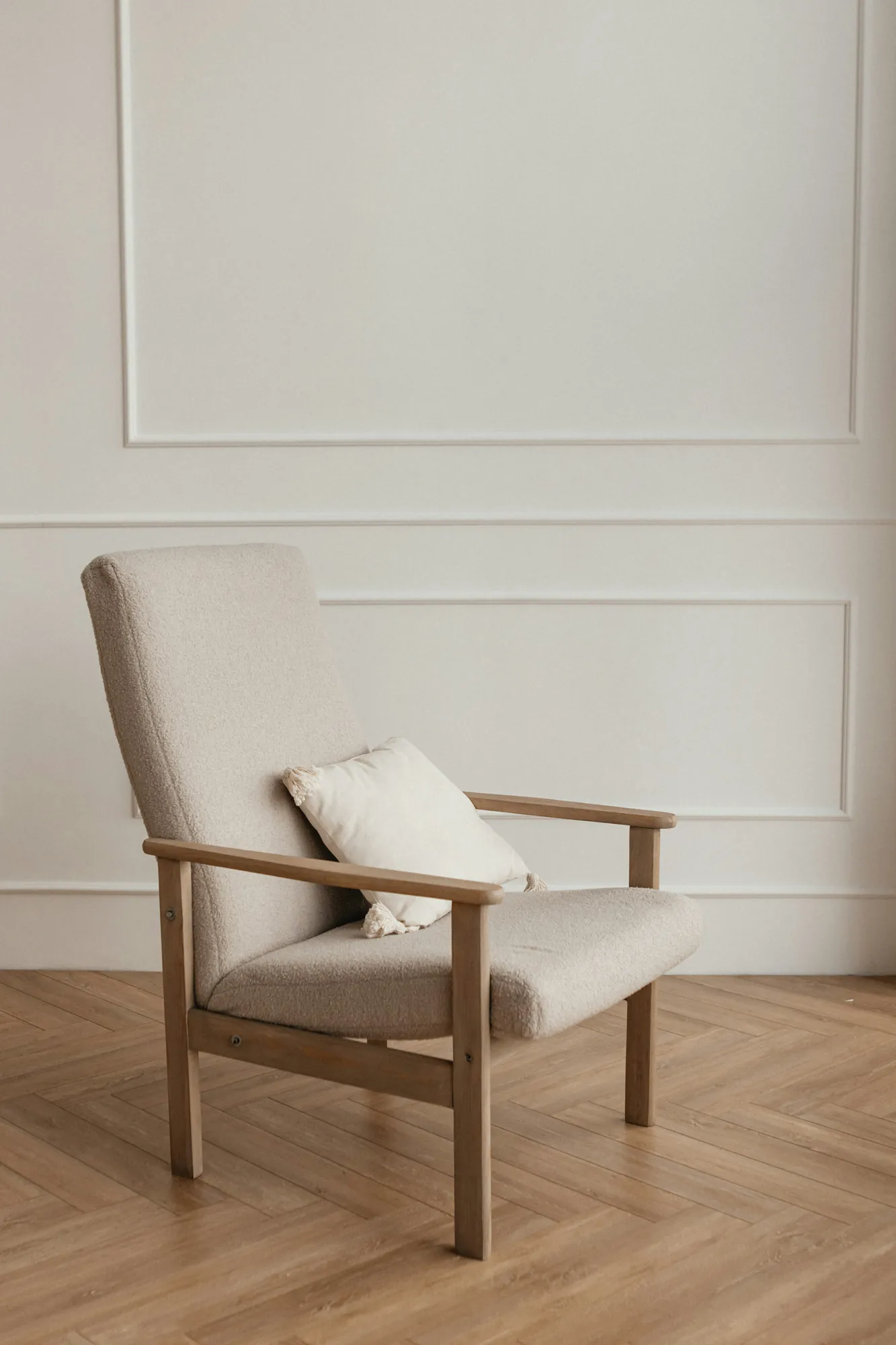 Ash lounge chair in oat bouclé against a panelled wall
