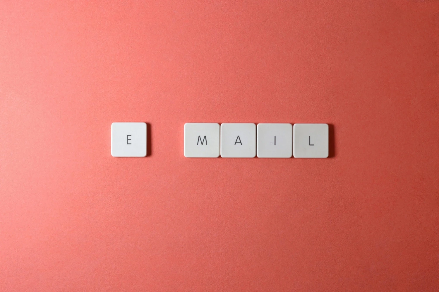 the word email written in scrabble tiles on a coral background