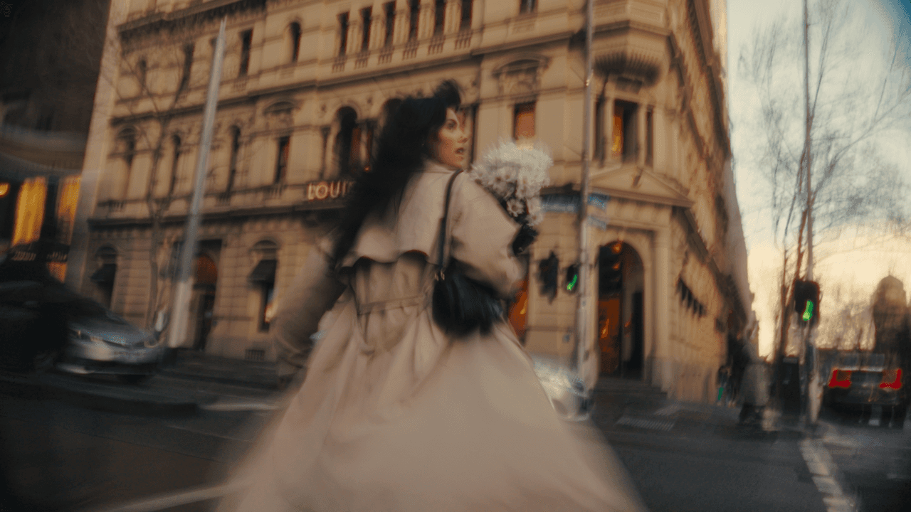 Back shot of a woman in a white gown walking towards a grand historic building, with intricate architectural details