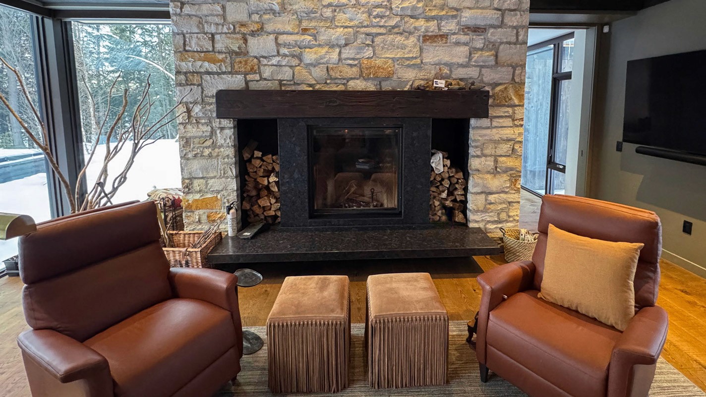 Modern summer house with leather chairs and stone hearth.