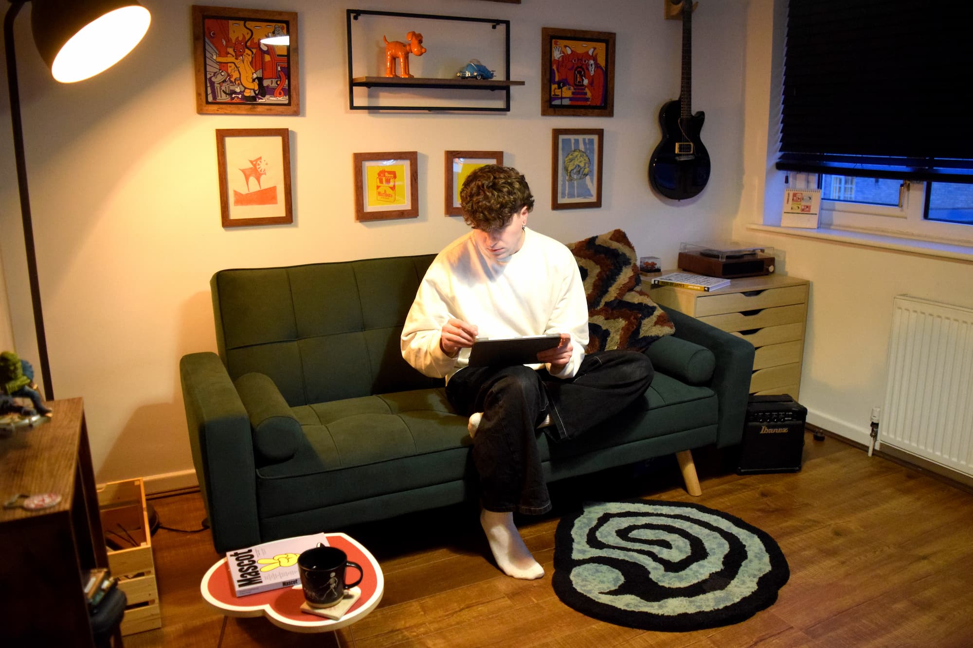 Designer of Upheaval sat on sofa in branding studio.