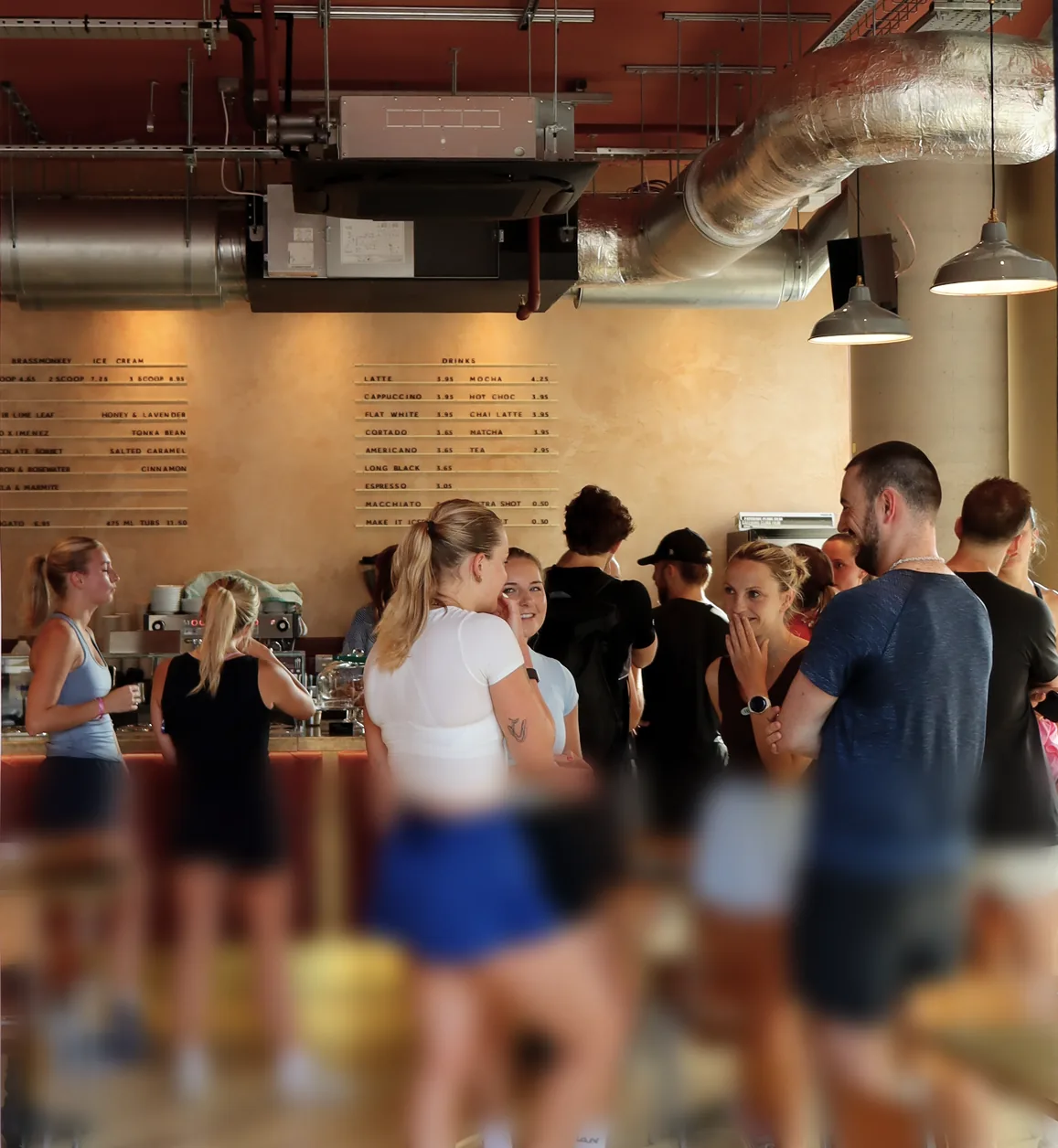 A crowd in activewear chatting at a busy café counter