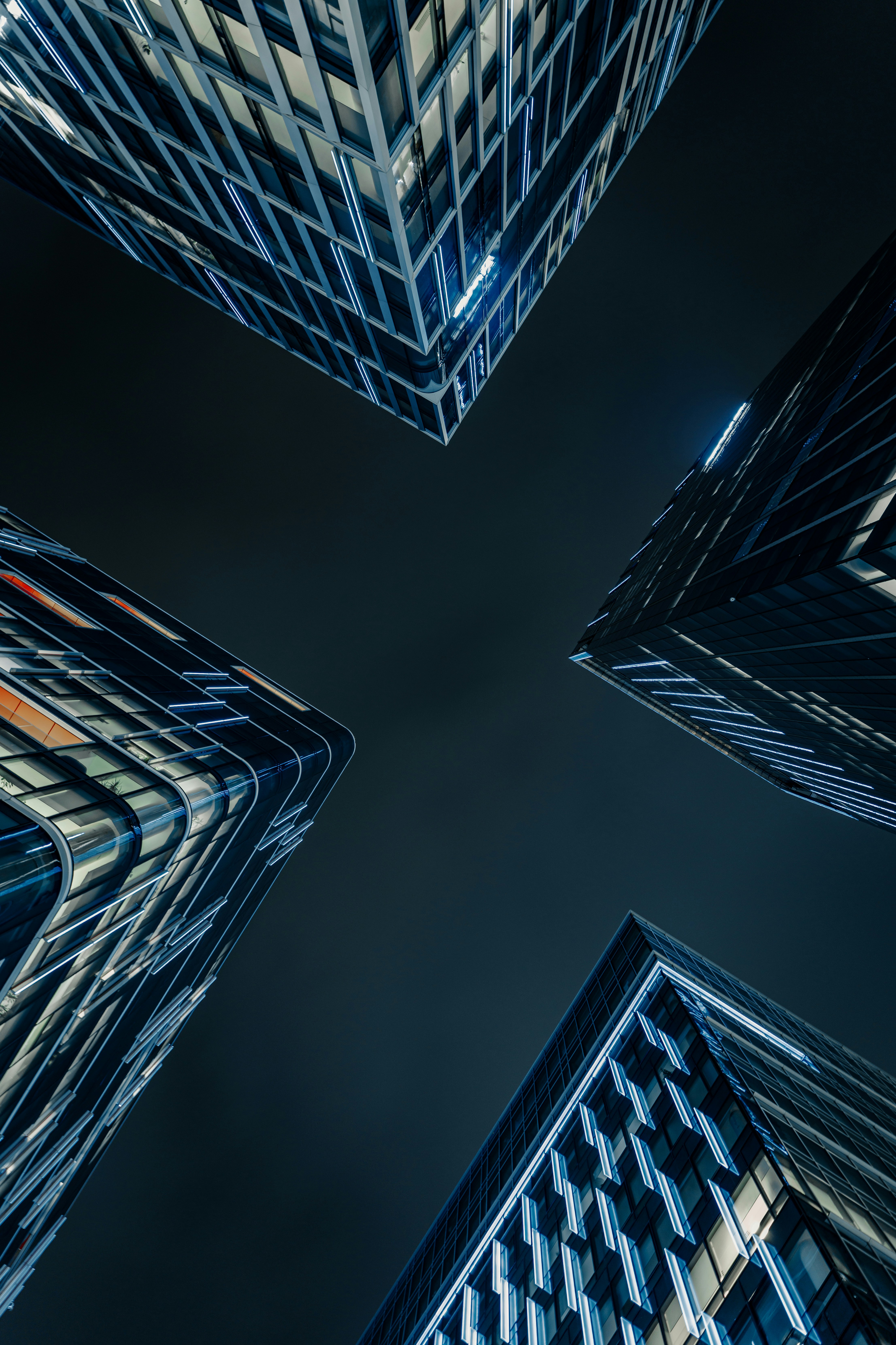 Modern skyscrapers viewed from below at night.
