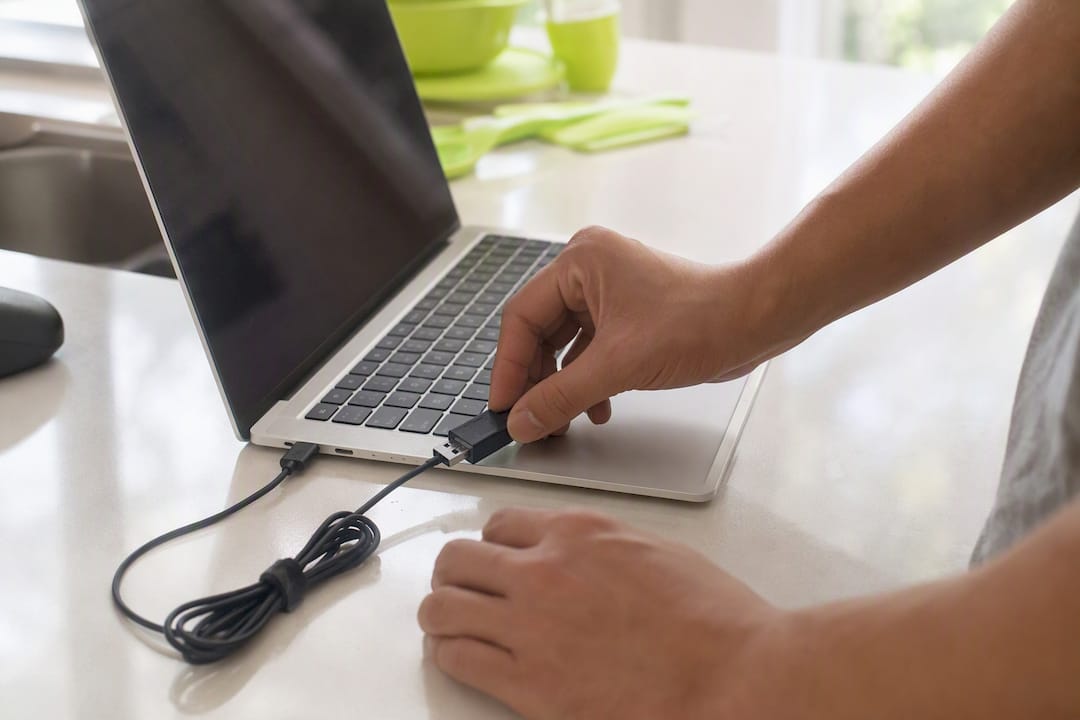 Hands plugging debugging device into laptop