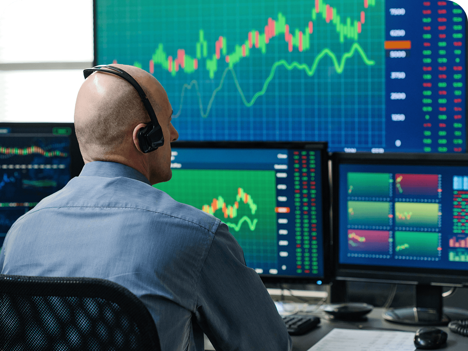 Person with headset analyzing stock charts on monitors