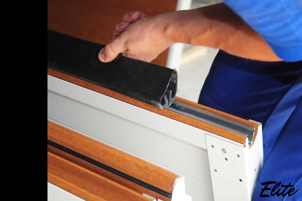 Replacing a worn rubber seal on a garage door to prevent drafts and freezing during winter in NWA | Northwest Arkansas Garage Door Repair & Installation