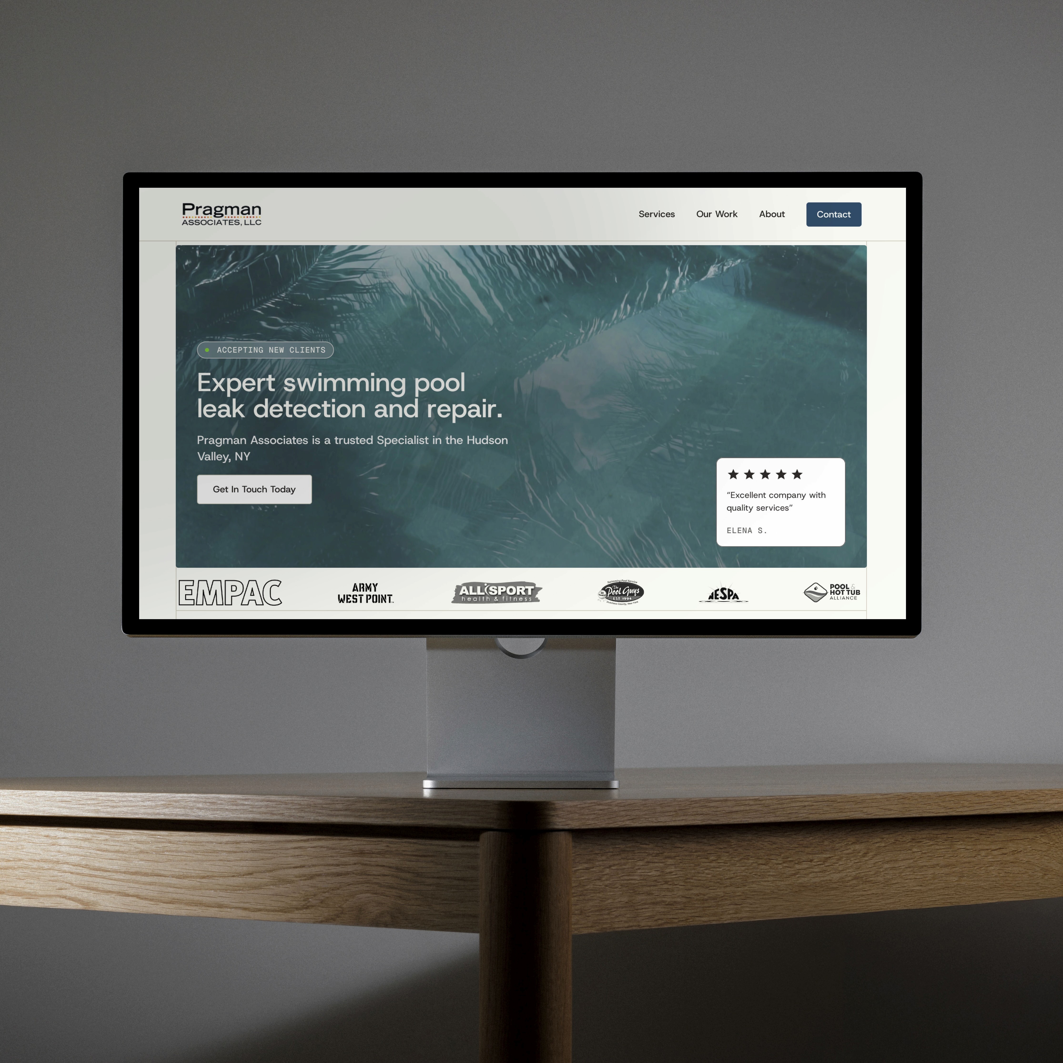 A desktop monitor mockup on a wooden desk displaying the homepage for Pragman Associates, LLC. The design features a high-resolution hero image of a swimming pool with a text overlay for 'Expert swimming pool leak detection and repair.' The layout includes a clear navigation bar, a 'Get In Touch' call-to-action button, a customer testimonial card, and a row of partner logos at the bottom.
