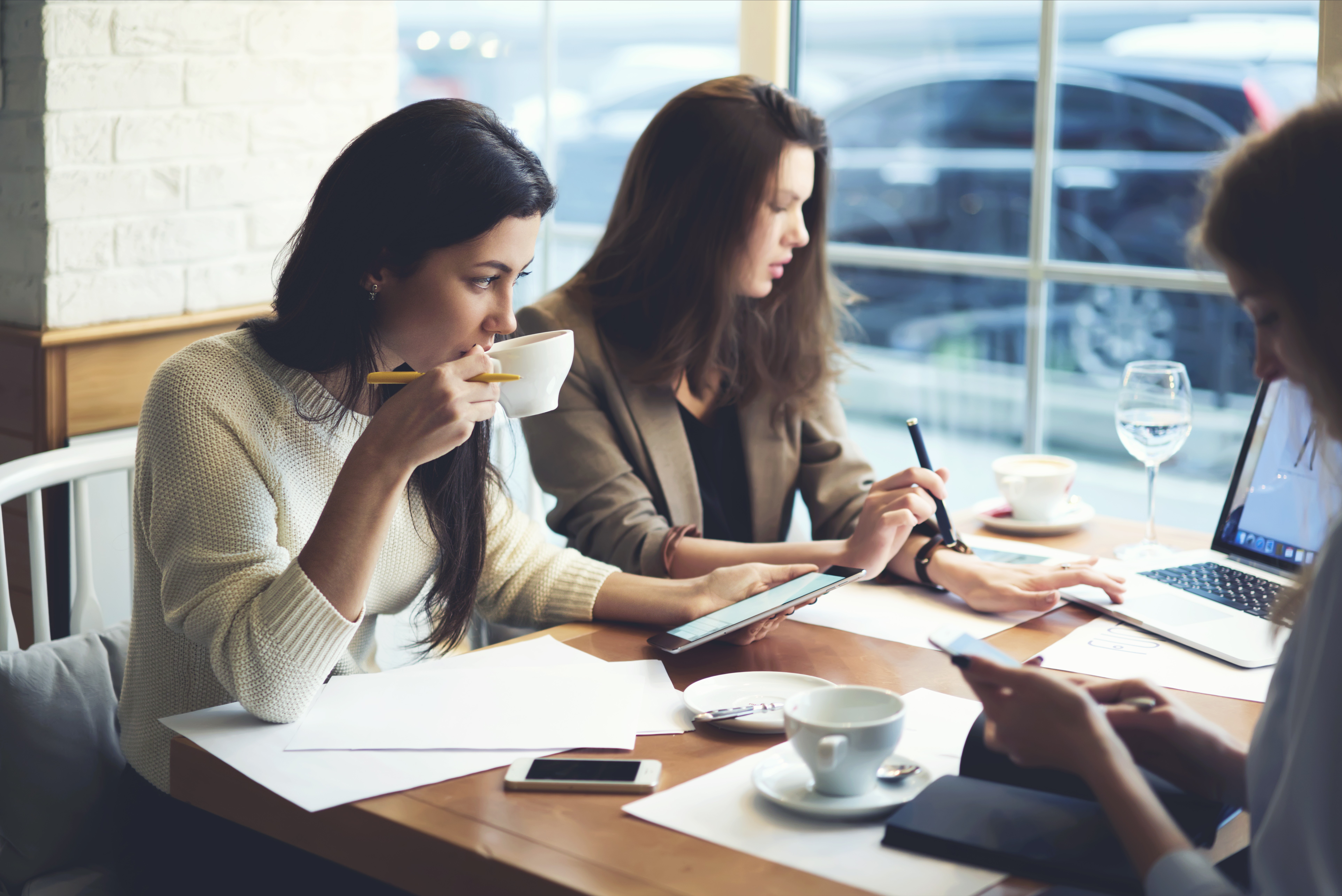Image of a freelancer web design team collaborating with client in coffee shop.