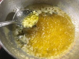 Ghee, the ayurvedic superfood, boiling in the kadhai and white coloured beri in the spoon.