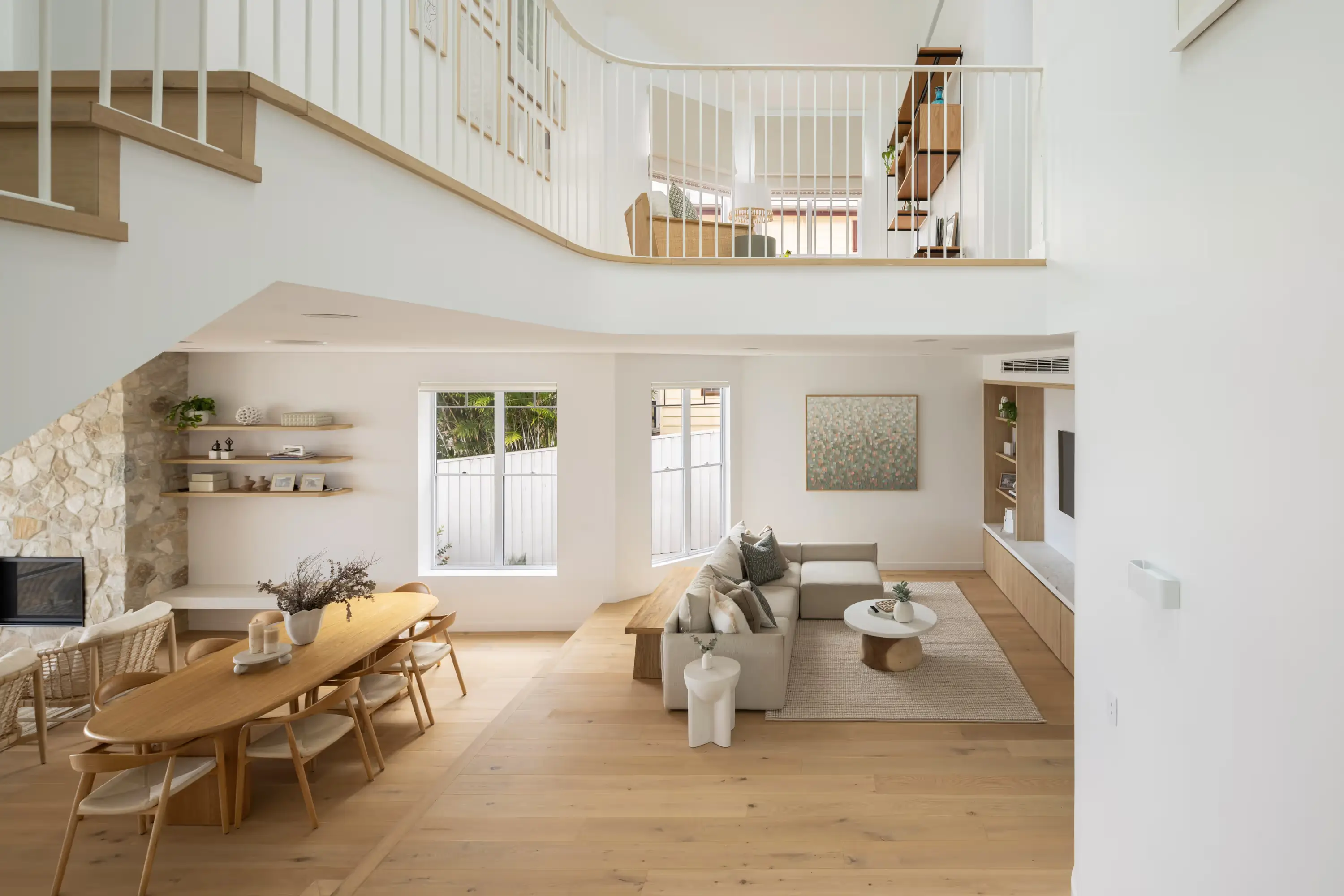 Zoned living spaceswith living stepping down ton dining with view of upstairs living space through the bannister