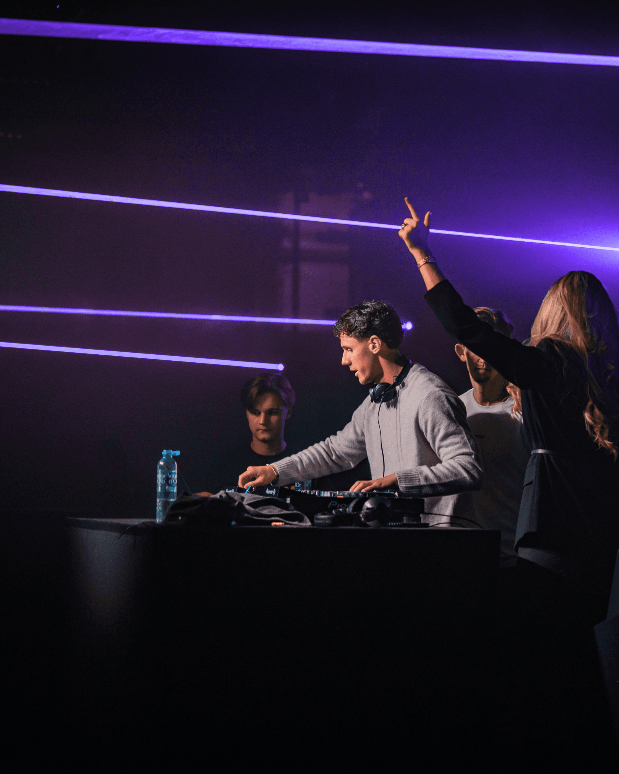 Studio portrait of a young person with blond hair, wrapped in translucent orange fabric against a blue background