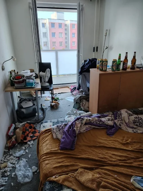 Obytný pokoj s postelí a balkonovými dveřmi před vyklizením