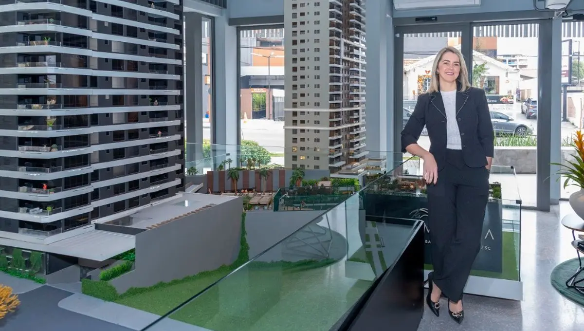 Adriana Moura ao lado de uma maquete de imóvel sustentável