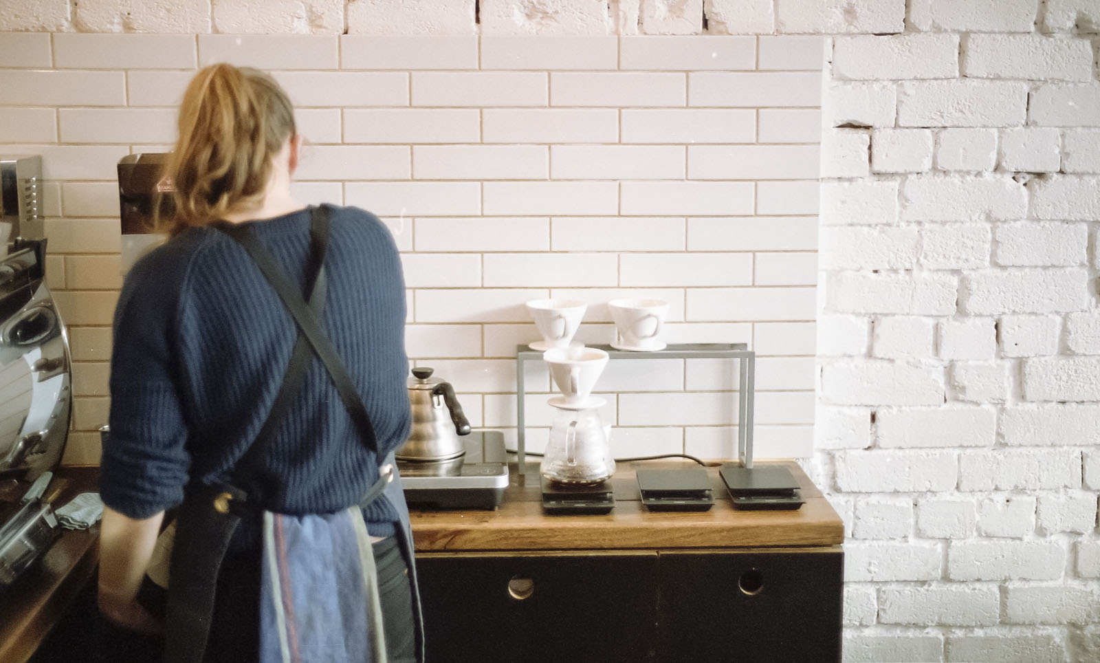 Female barista making coffee with back to camera