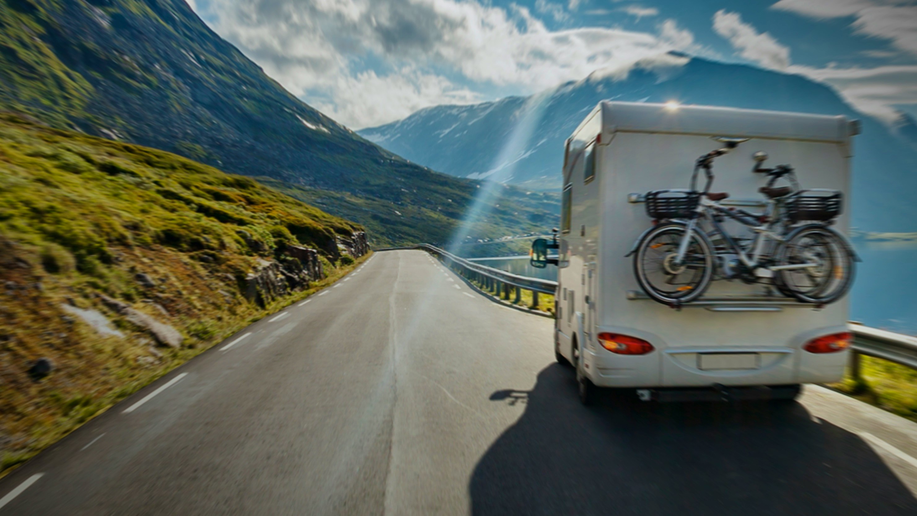 Campercontact — rear view of a motorhome with bicycles on the back driving through a scenic mountain road — Soda Studio case study